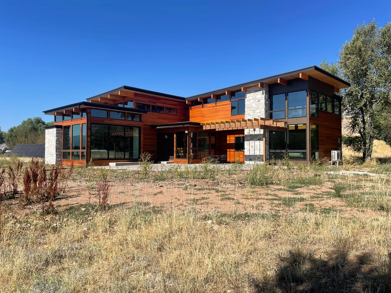 Utah modern home rear elevation with wood, stone, and broad window walls